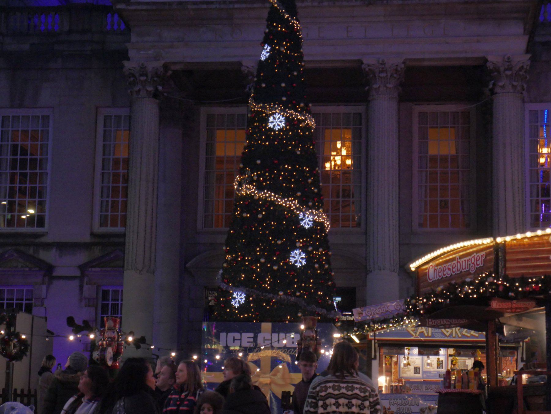 Christmas tree wrapped in lights and snowflakes in front of a columned building at the Leeds Christmas market