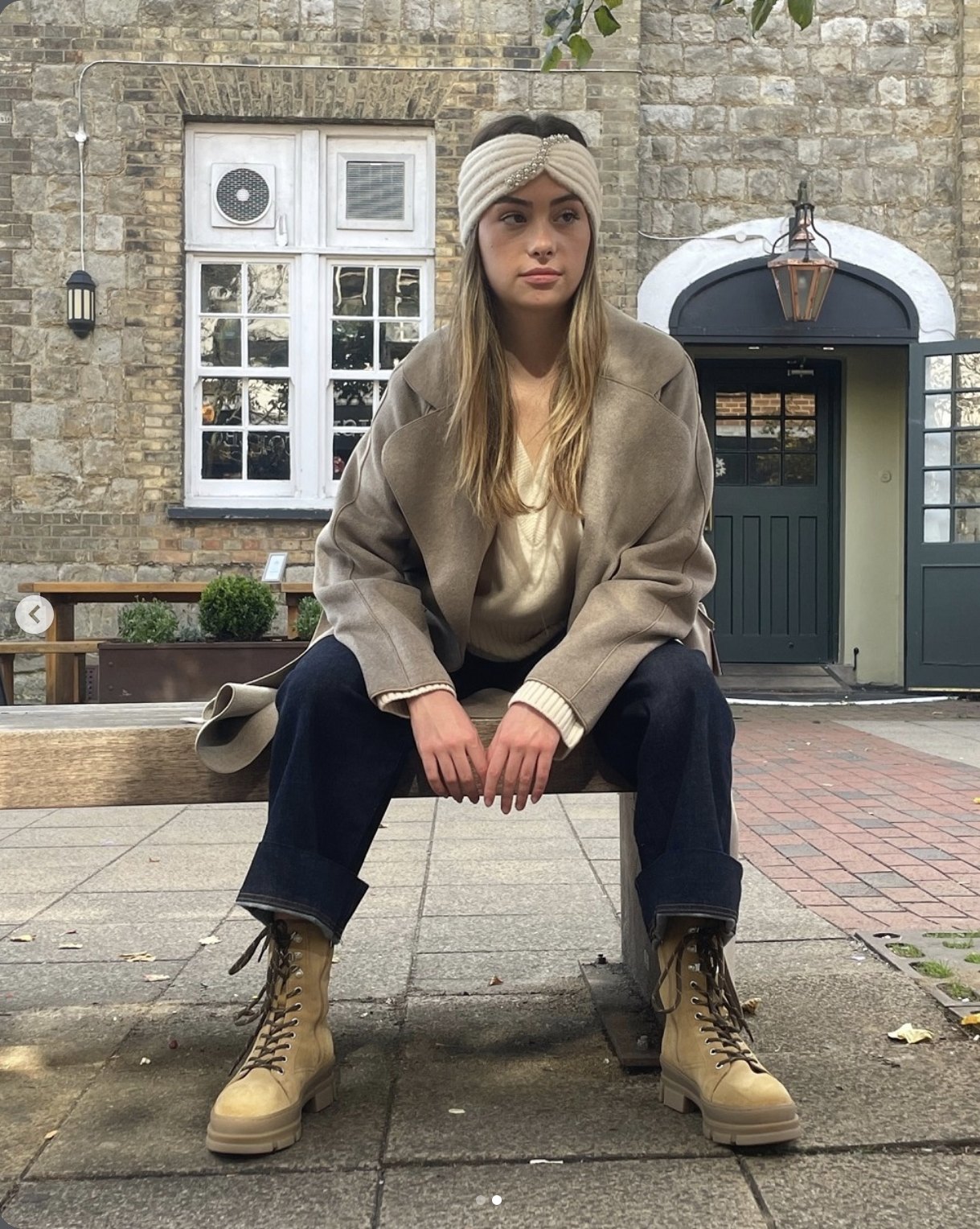 Cover: model seated on a bench in a beige coat, jewelled headband and suede boots