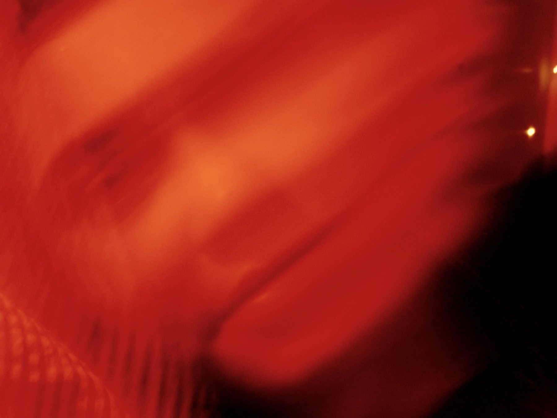 Close, heavily blurred face in glowing red and orange light
