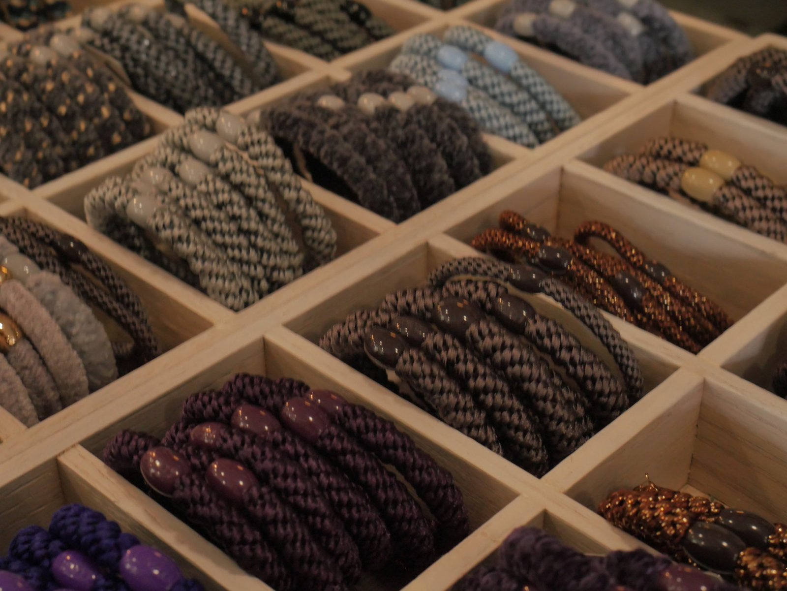 Trays of woven hair ties in purple, grey and copper tones