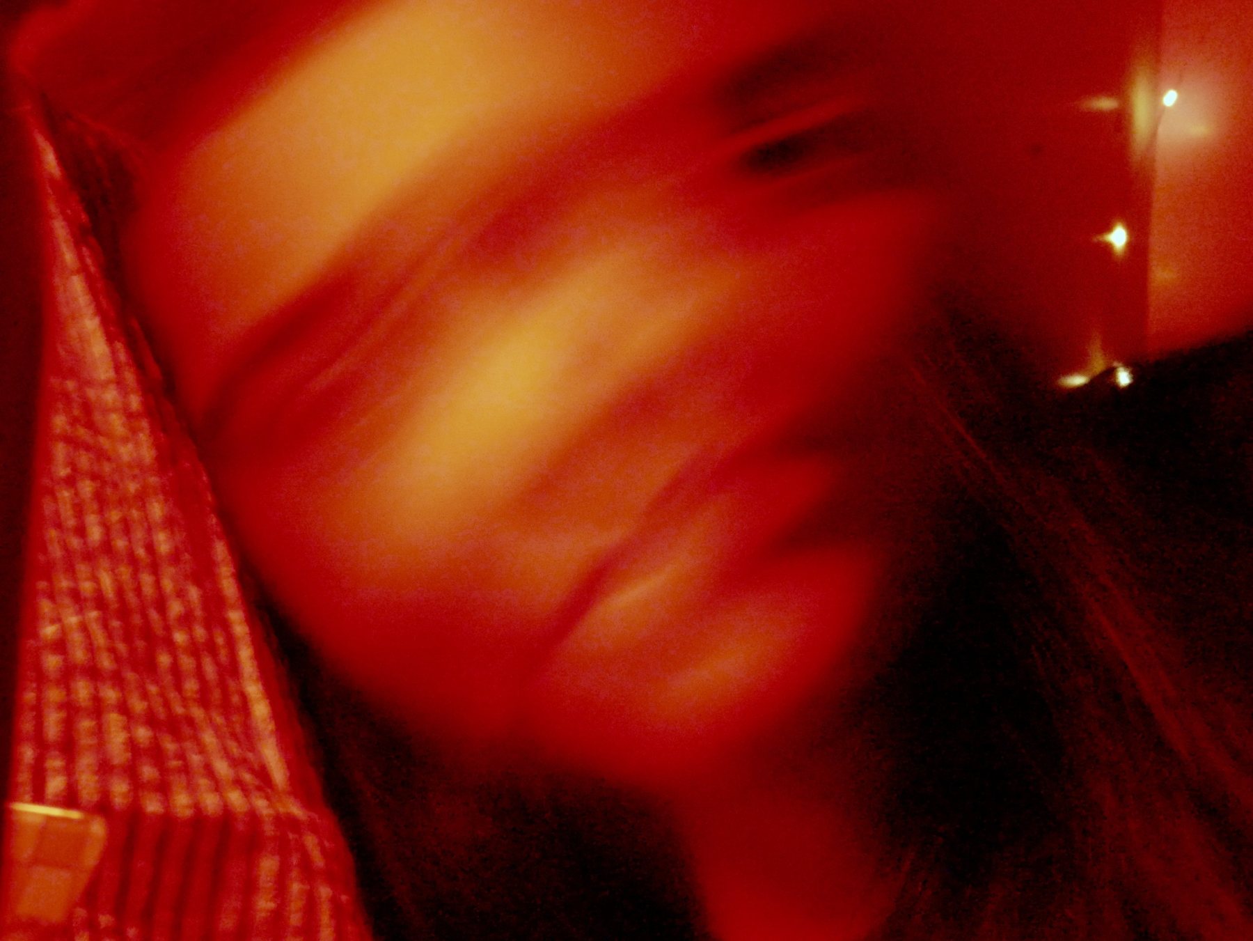 Figure caught mid-movement under red and violet light with fairy lights behind